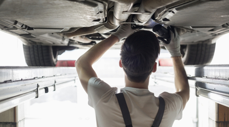 technician inspects under car