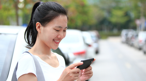 woman using phone on car lot